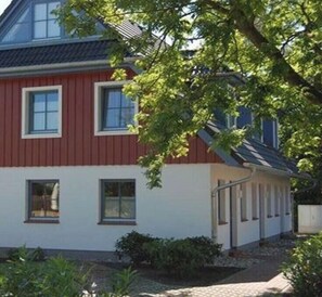 Ein rot-weißes Gebäude mit vielen Fenstern und einem überdachten Vorbereich.