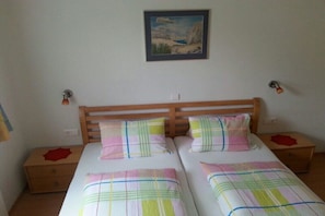 Ein Schlafzimmer mit zwei Betten, einem Holzkopfende, Nachttischen und einem Gemälde an der Wand.