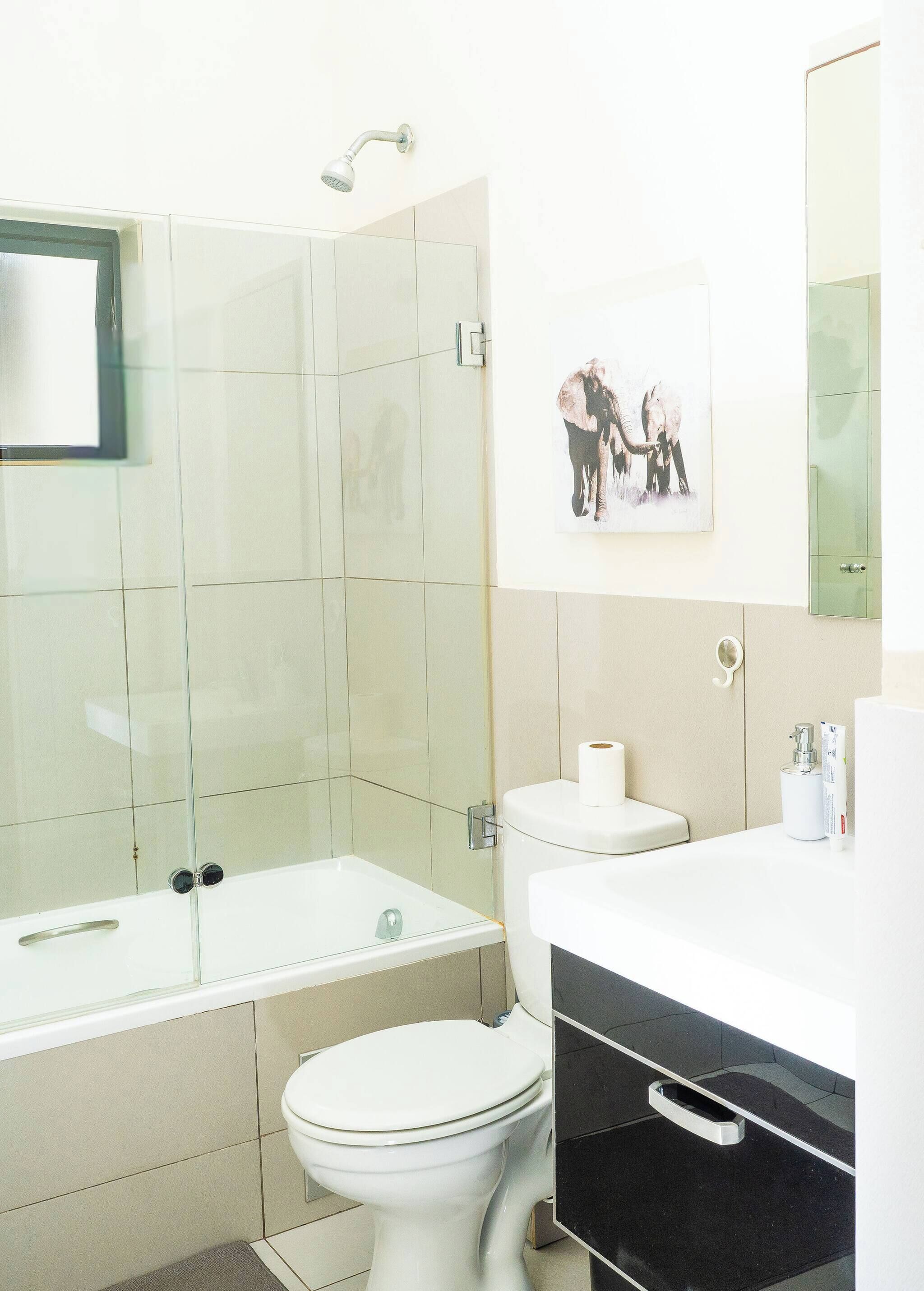 Un baño con ducha acristalada, inodoro y lavamanos.