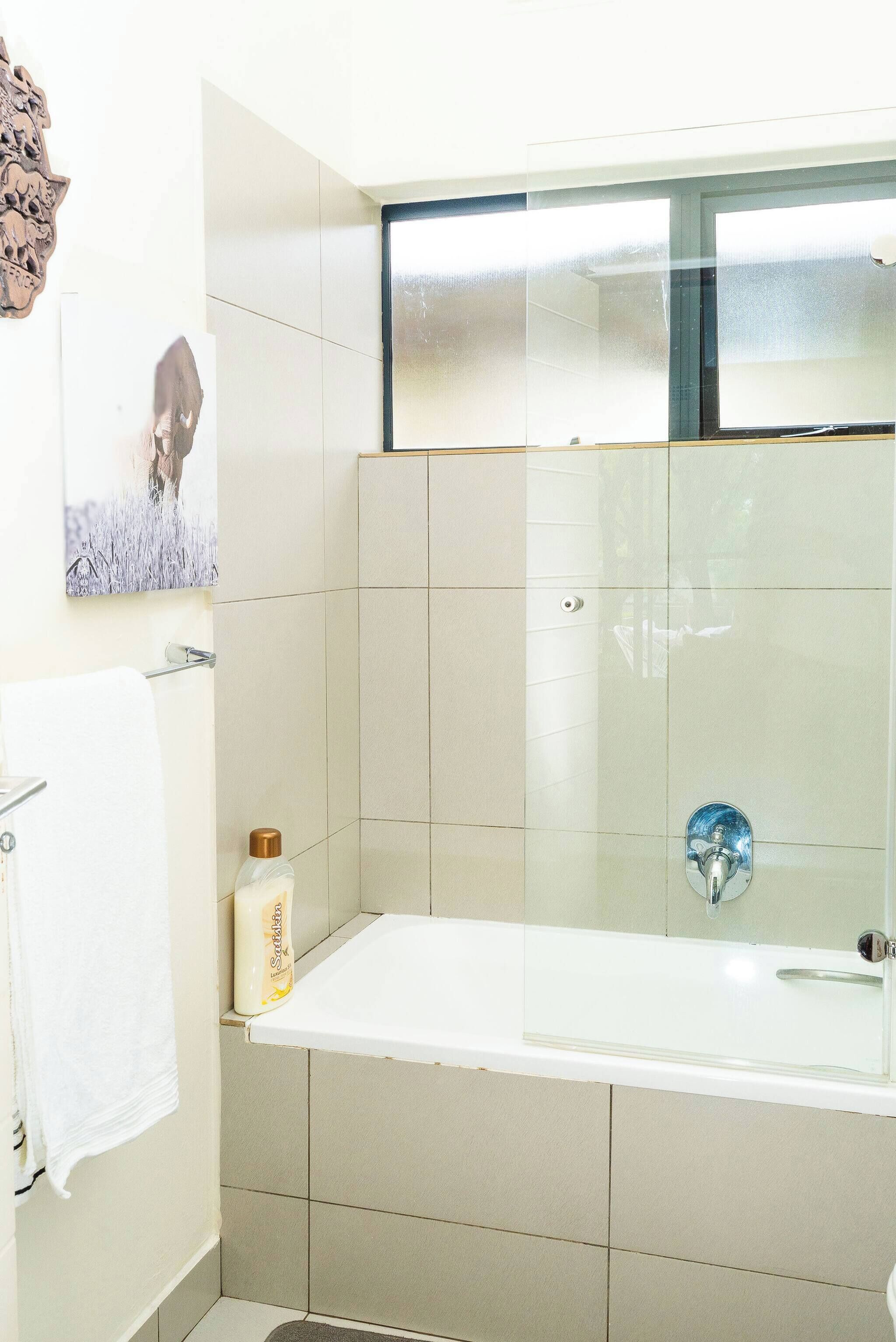 Een badkamer met een bad, een douchecabine van glas en een handdoekhouder.