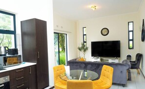 Un espacio habitable moderno con cocina, comedor y televisor de pantalla plana.