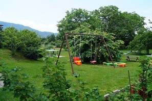 Ein Garten mit Schaukel, Picknicktisch und üppigem Grün.