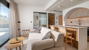 En moderne stue med sofa, et lille bord og et køkkenområde med en bar.