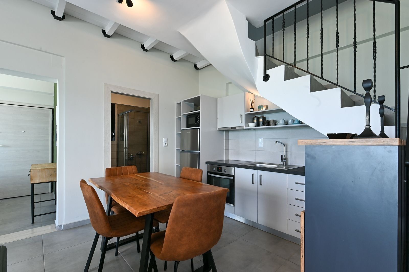 Una cocina moderna con comedor, una escalera y vistas al exterior.