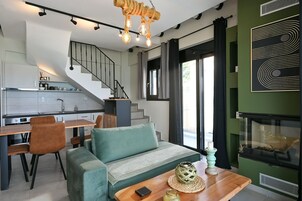 Un interior moderno con una escalera, un sofá, una mesa de comedor y una chimenea.