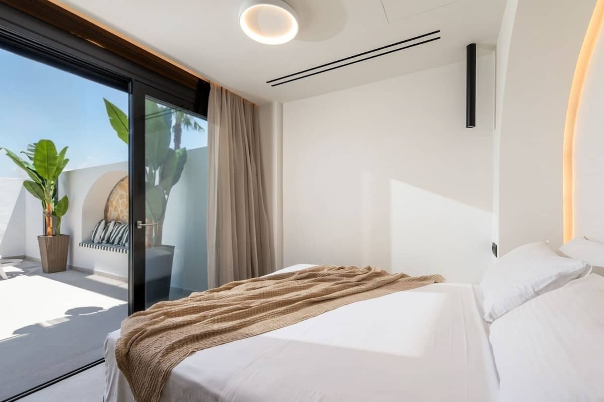 A modern bedroom with a bed, a large window, and a balcony with a plant.
