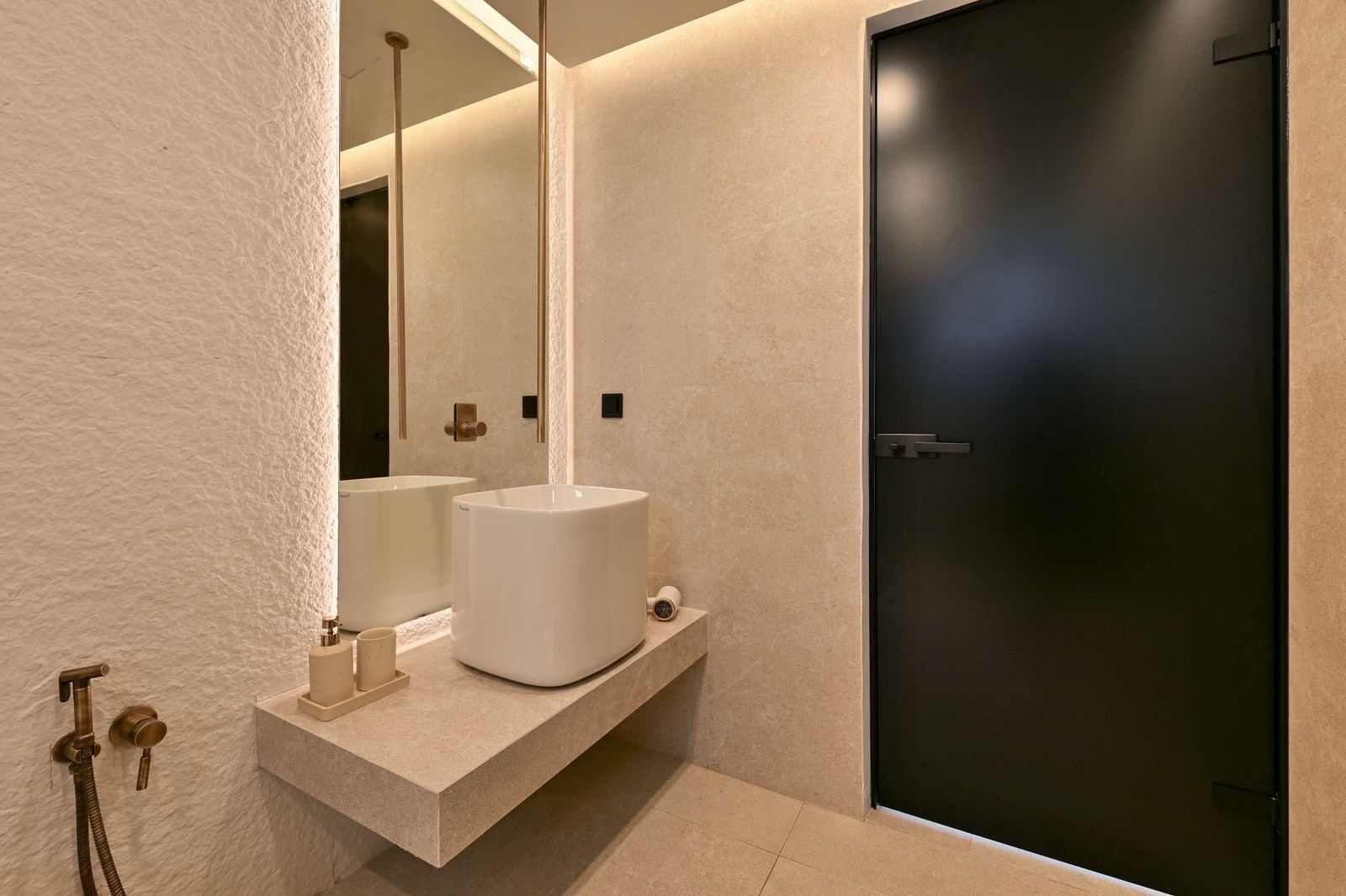 A modern bathroom with a large white sink, a dark door, and a towel rack.