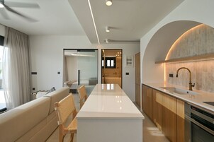 Una cocina moderna con una isla central, armarios de madera y un lavamanos de acero inoxidable.