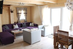 A wooden interior with a sofa, ottoman, and dining table.
