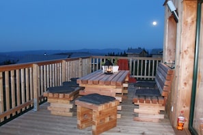 A wooden deck with a table and benches, overlooking a body of water and hills. - Cabin in Carinthia with 3 bedrooms (Bad Sankt Leonhard)