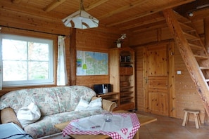 A wooden cabin interior with a sofa, a map on the wall, a staircase, and a small stool. - Holiday home in Altwarp with swimming pool (Altwarp)