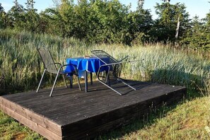 A wooden deck with a table and chairs set up for outdoor dining. - Holiday home in Altwarp with swimming pool (Altwarp)