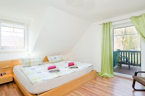Ein Schlafzimmer mit Bett, Nachttisch, Fenster und einem Balkon mit Stuhl.
