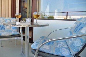 Ein Balkon mit zwei Stühlen und einem Tisch, jeweils mit einem Weinglas.