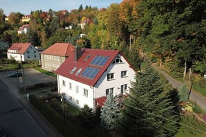 Un edificio residencial con techo inclinado, paneles solares y un jardín.