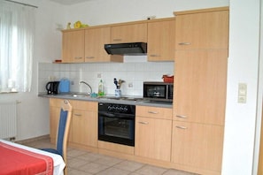 Eine kleine Küche mit Holzausstattung, einem Backofen, einer Mikrowelle und einem Spülbecken.