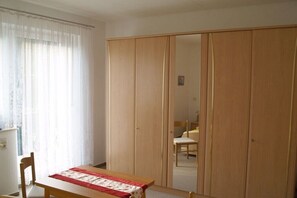 Ein Zimmer mit einem Holzschrank, einem Tisch mit rotem und weißem Tuch und einem Stuhl.