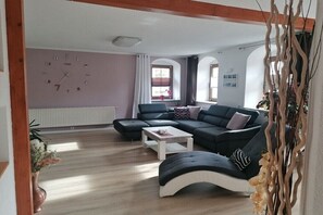 Ein Wohnzimmer mit Ecksofa, Couchtisch und Wanduhr.