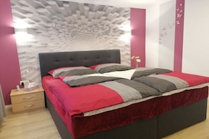 Ein Schlafzimmer mit einem modernen Bett, einem Nachttisch und einer Wand mit besonderer Struktur.