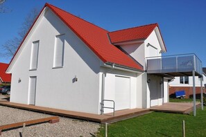 Ein eingeschossiges Gebäude mit rotem Dach, einer Garage und einer überdachten Veranda.