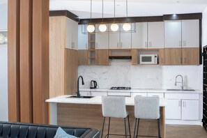 Una cocina moderna con armarios de madera, encimera de mármol, cocina a gas y microondas empotrado.