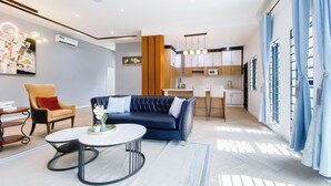 A modern living room with a sofa, a coffee table, and a dining area with chairs. - 3 beds Villa with BBQ grill and very fast wifi (Douala)