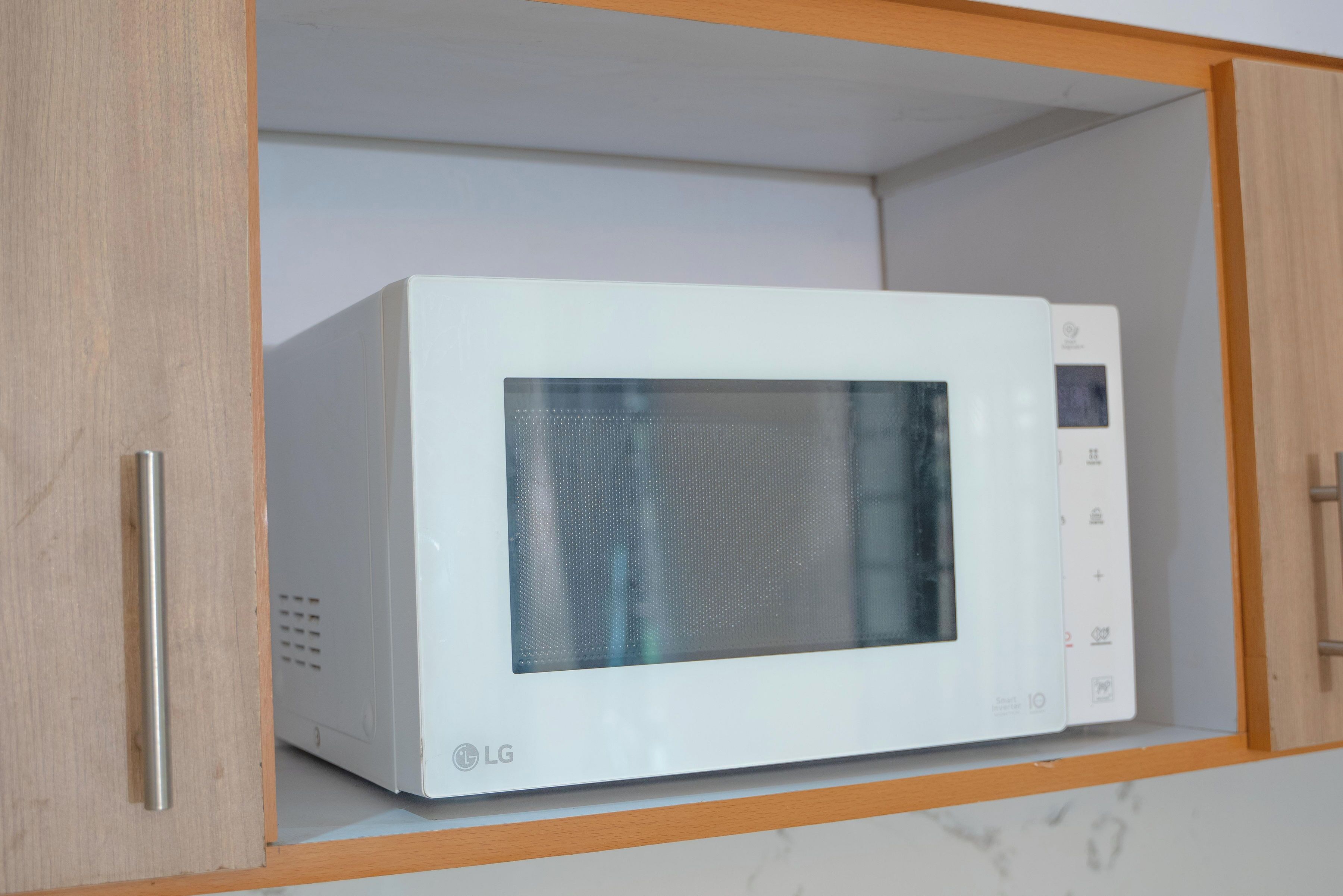 Un microondas blanco dentro de un mueble de cocina con marco de madera.