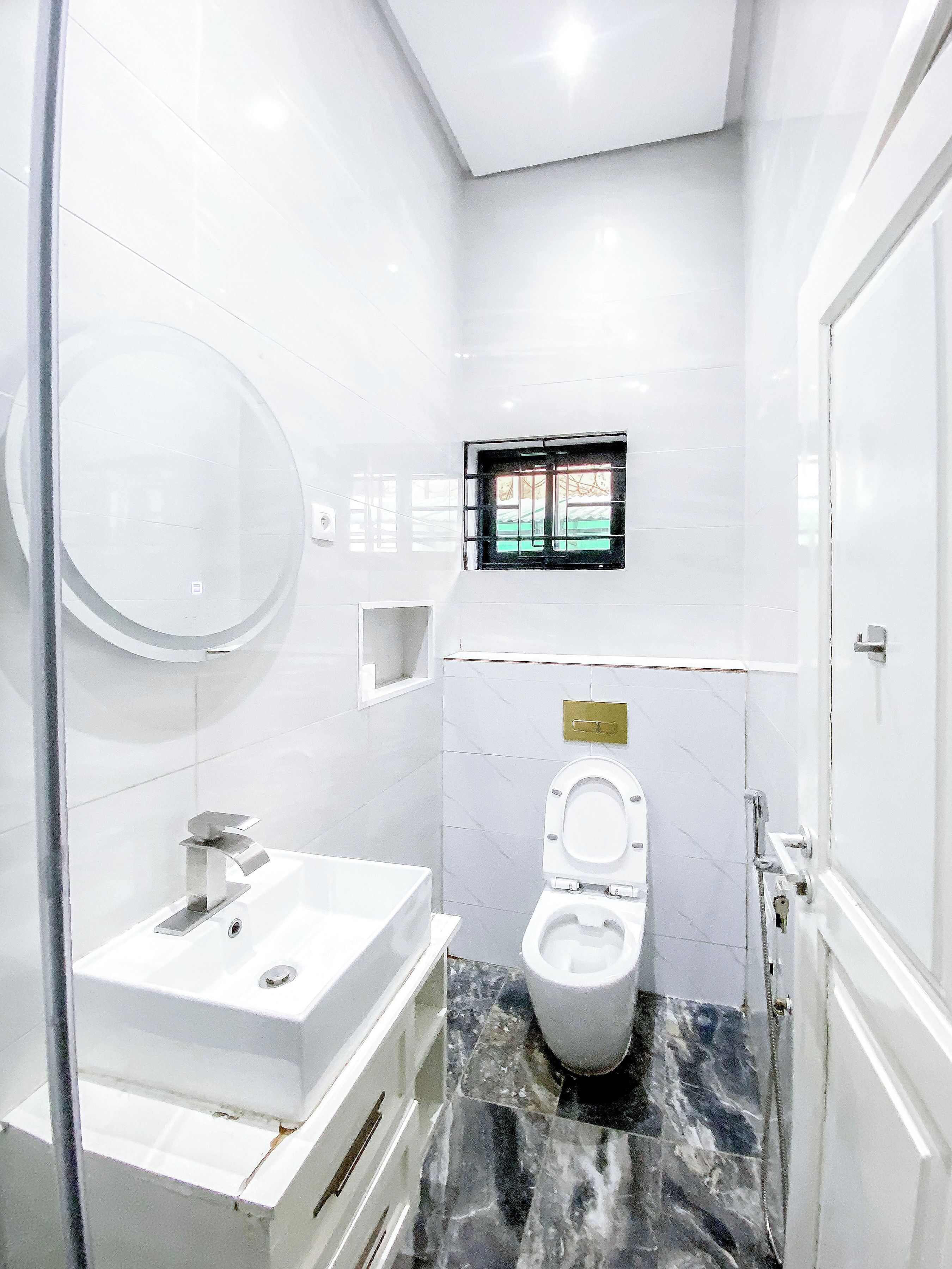 Casa de banho moderna com lavatório branco, sanita e janela com grades.