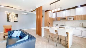 A modern kitchen with white cabinets, a central island, and a dining area with two chairs. - 3 beds Villa with BBQ grill and very fast wifi (Douala)