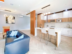 A modern kitchen with white cabinets, a central island, and a dining area with two chairs.