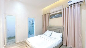 A modern hotel room with a bed, a shower, and a painting on the wall. - 3 beds Villa with BBQ grill and very fast wifi (Douala)