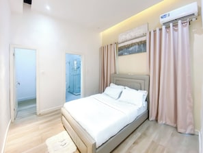 A modern hotel room with a bed, a shower, and a painting on the wall.