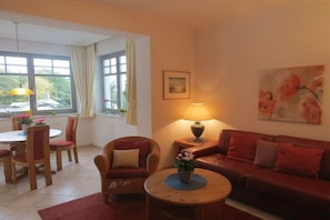 Ein Wohnzimmer mit einer Couch, Stühlen, einem runden Tisch und einer Lampe.