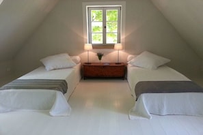 Ein Schlafzimmer mit zwei Betten, einem Fenster und einem Nachttisch mit Lampen.