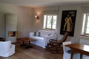Ein gemütliches Wohnzimmer mit einem weißen Sofa, einem Holzschaukelstuhl, einem kleinen Tisch und einem Kamin.