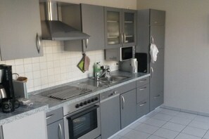 A modern kitchen with grey cabinets, a stainless steel range hood, a built-in microwave, and a stainless steel refrigerator. - Holiday apartment with 2 bedrooms (Otterndorf)