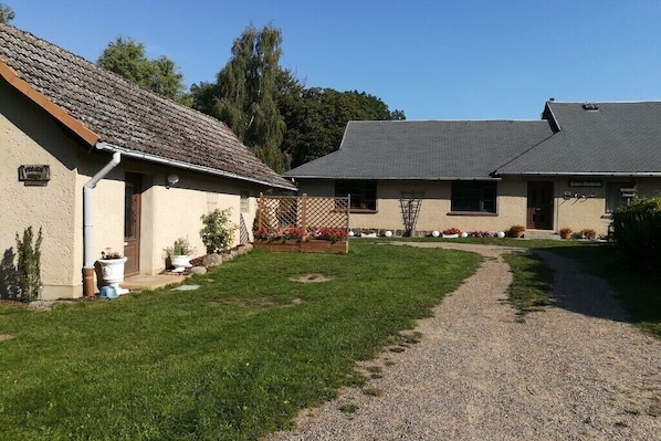 A building with a gravel driveway and a grassy area with potted plants. - Lake view - Varchentin (Varchentin)