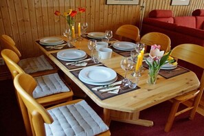 Mesa de madera para cuatro personas, con sillas, velas y flores.