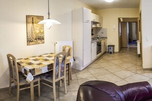 Ein Essbereich mit Tisch, Stühlen, einer Hängeleuchte und einer Küche im Hintergrund.