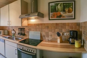 A kitchen with a stove, sink, and coffee maker. - Holiday apartment with 1 bedroom (Ostseebad Binz)