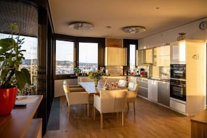 A modern kitchen with a dining area, large windows, and a view of the city. - Skyflats Vienna West View (Wien)