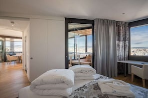 A modern hotel room with a bed, a desk, and a view of the city. - Skyflats Vienna West View (Wien)
