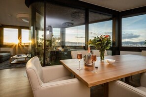 A modern dining area with a wooden table, white chairs, and a city view. - Skyflats Vienna West View (Wien)