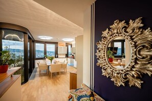 A modern interior with a dining area, a large ornate mirror, and a view of the city. - Skyflats Vienna West View (Wien)