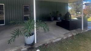 Una zona de pati coberta amb plantes en testos, una zona d'seients exteriors negre i una vista del paisatge circumdant.