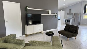 Un saló modern amb televisió de pantalla plana, un sofà i una taula auxiliar petita amb una planta.