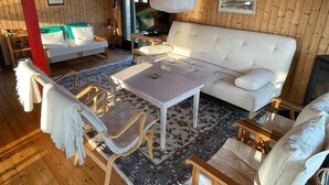 Un interior de madera con un sofá, sillas, una mesa y un televisor.
