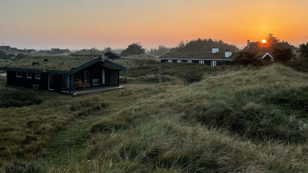 Un paisaje rural con una casa y un edificio pequeño con techo verde.