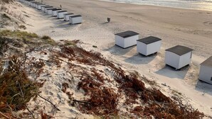 Una playa con estructuras blancas alineadas a lo largo de la orilla, posiblemente cabañas de playa o almacenes.