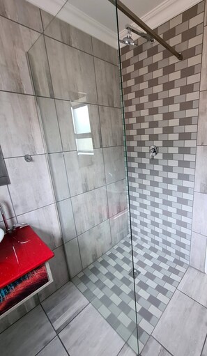 A bathroom with a glass shower enclosure, a red sink, and tiled walls. - Villa Du-baai 1 Luxury Apartment (Mossel Bay)
